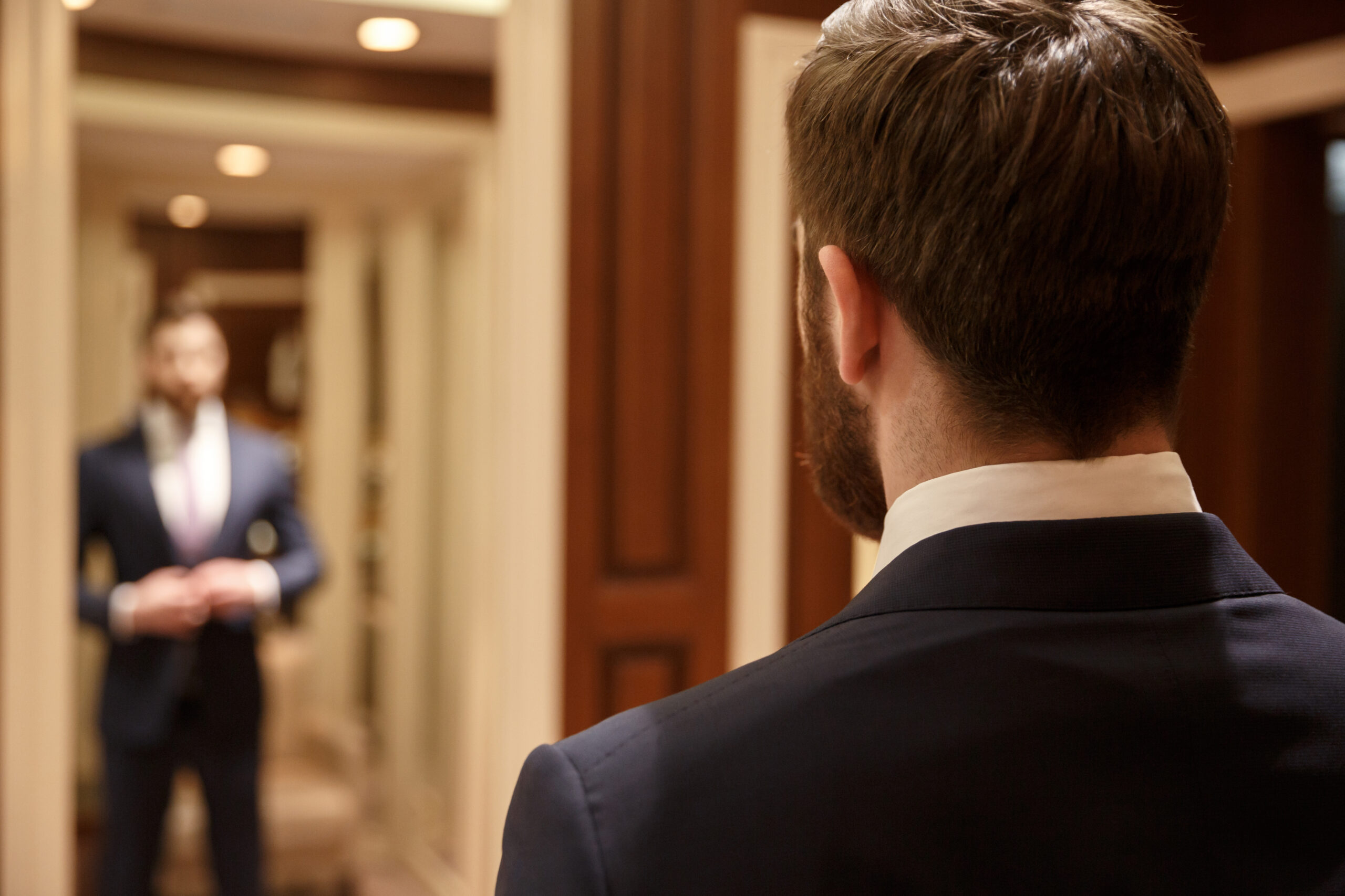 man wearing a suit looking in a mirror